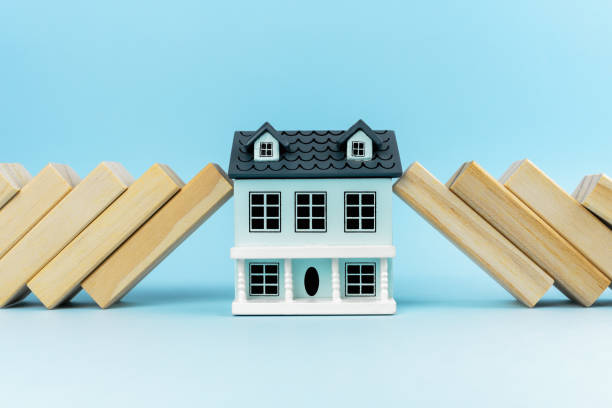 A stock image of a minaturized two-story house against a blue backdrop